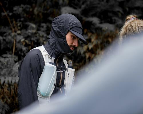A man on a bicycle is about to drink from the tube of his water bag