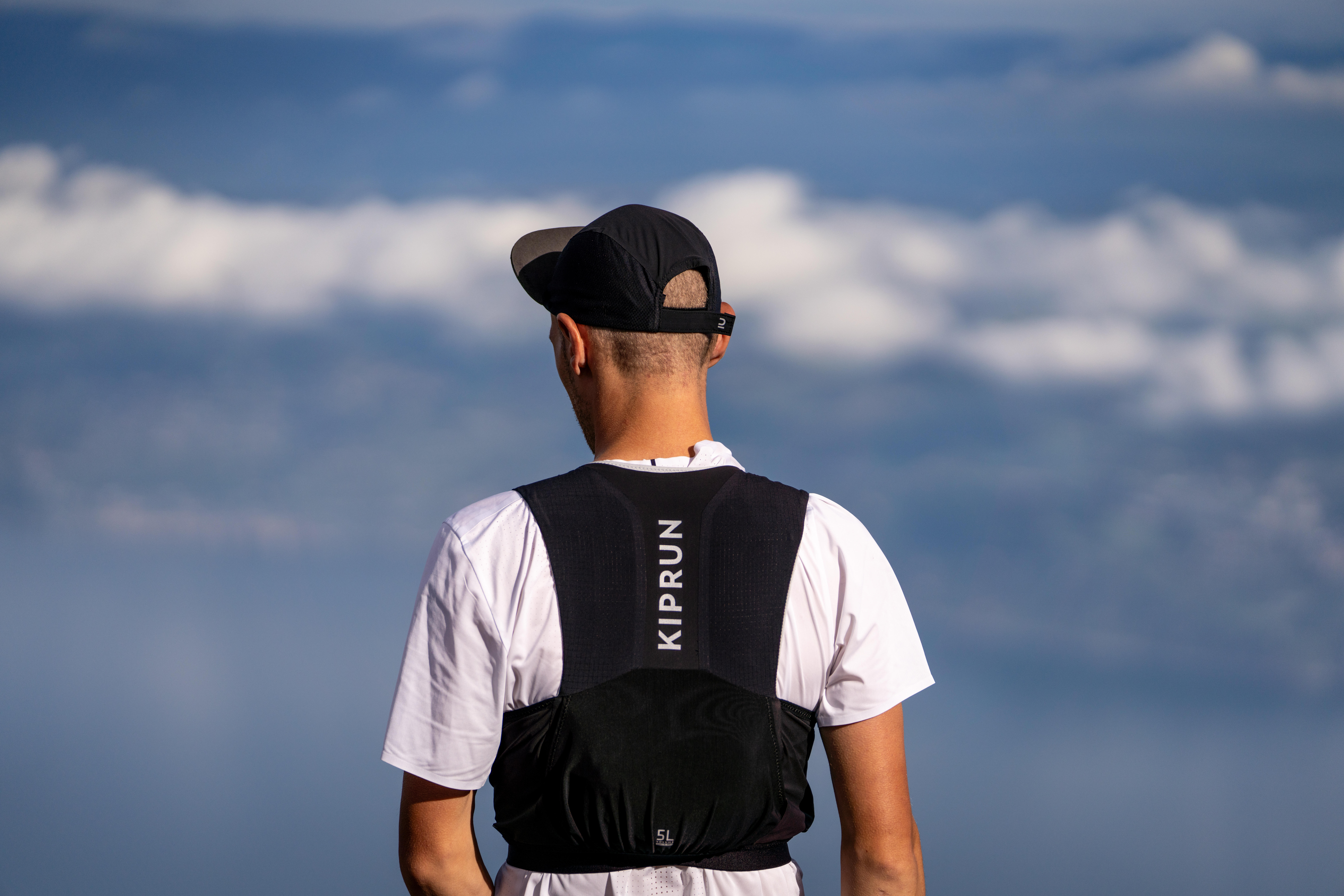 Runner wearing a black Kiprun hydration vest and cap on a mountain trail