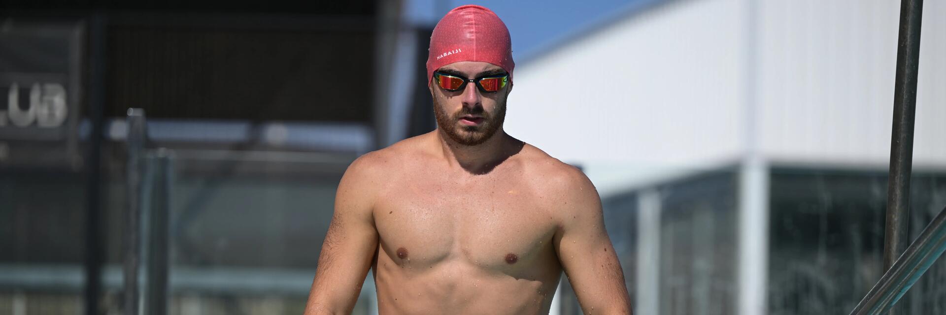 Mężczyzna stosujący dietę pływaka wchodzący do basenu w czepku i okularach pływackich