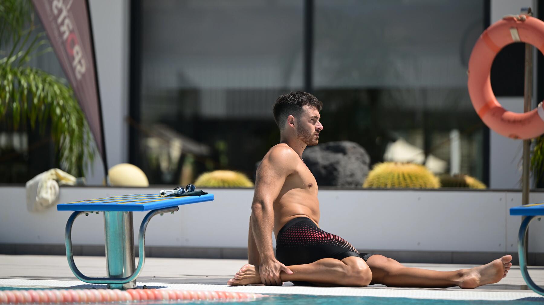 Ein Mann ist geschwommen und dehnt sich nach dem Sport