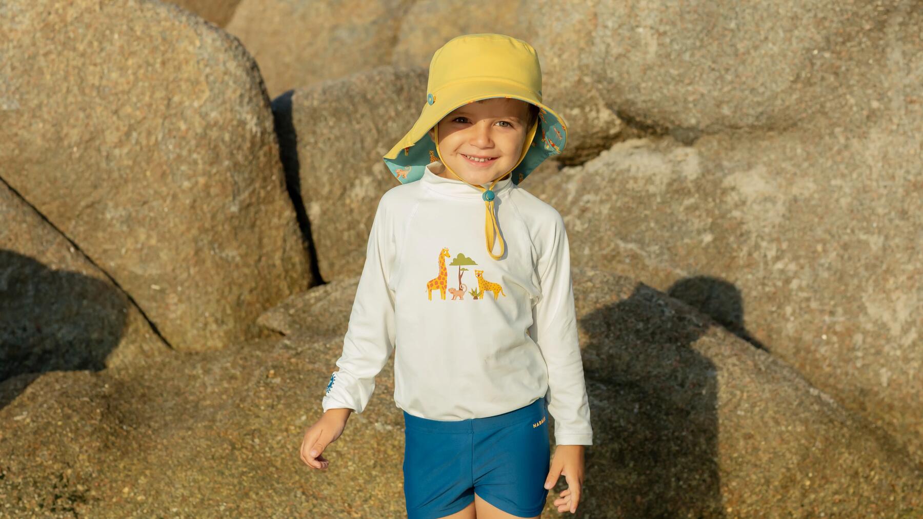 Ein Kind steht mit UV-Shirt vor einem Stein