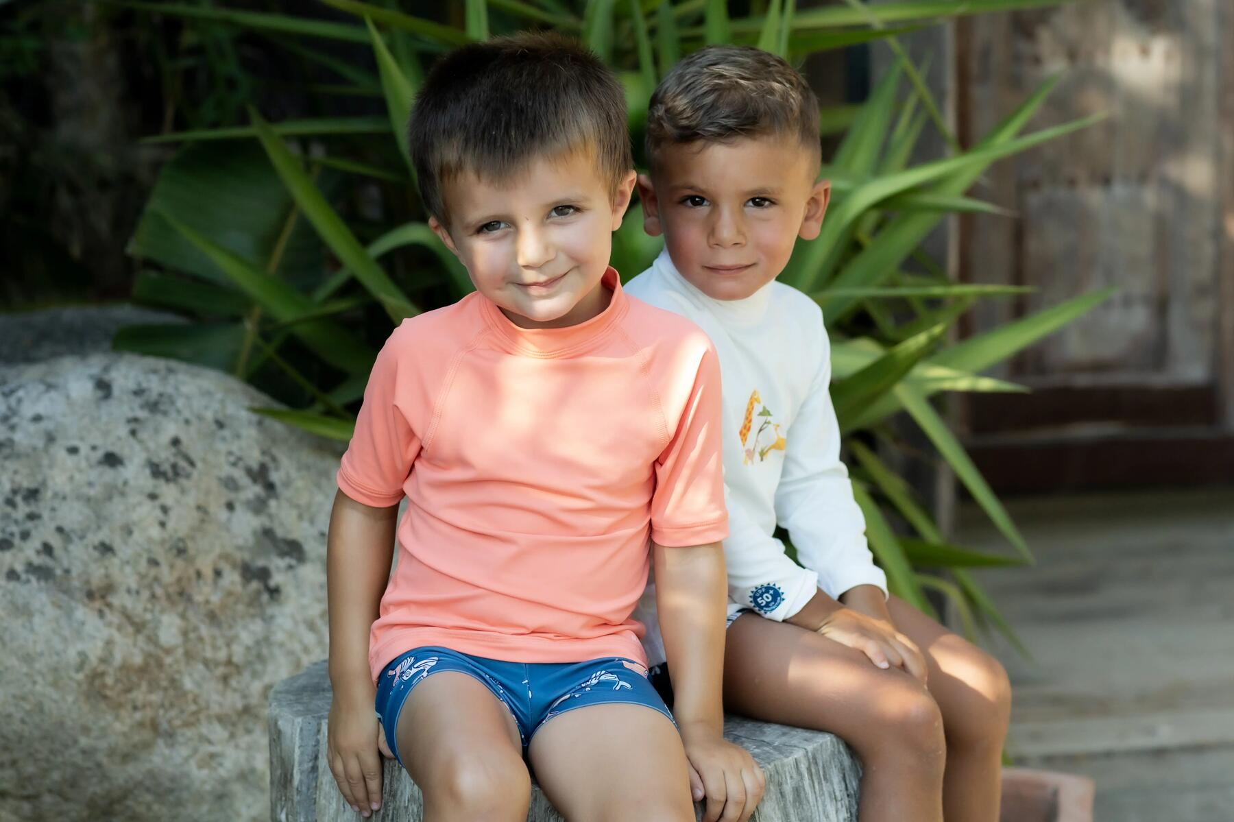 Zwei Jungs tragen UV-Shirts und sitzen auf einem Stein