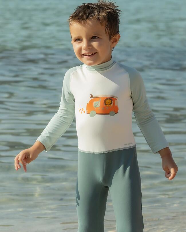 Kind steht vor dem Wasser am Strand, UV-Schwimmanzug