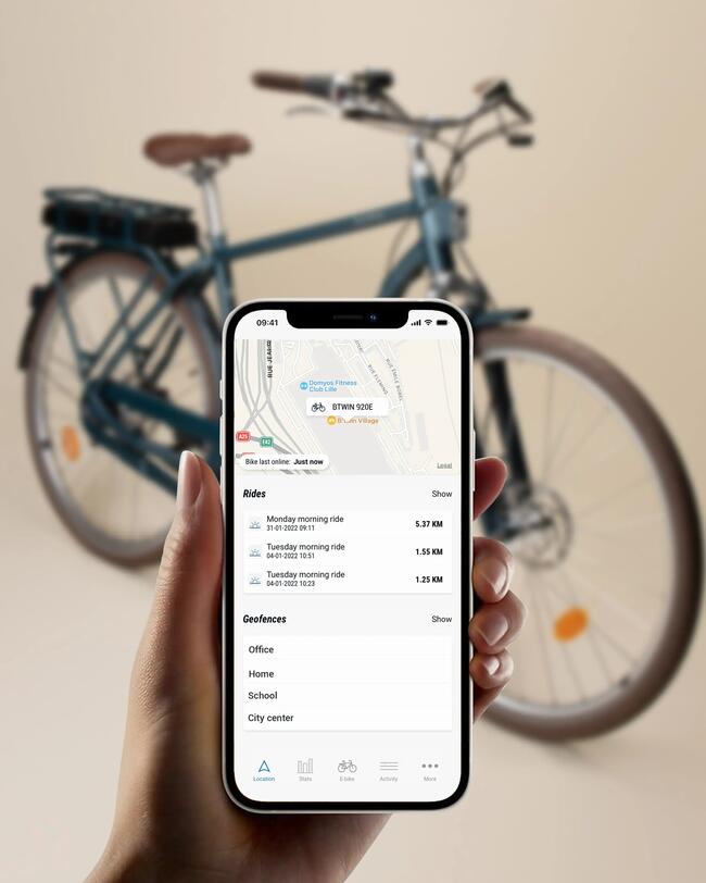 Hand hält Smartphone mit Konnekitvitätsapp darauf, im Hintergrund blaues Fahrrad