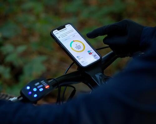 Rowerzysta korzystający z telefonu przymocowanego do kierownicy za pomocą uchwytu na telefon do roweru