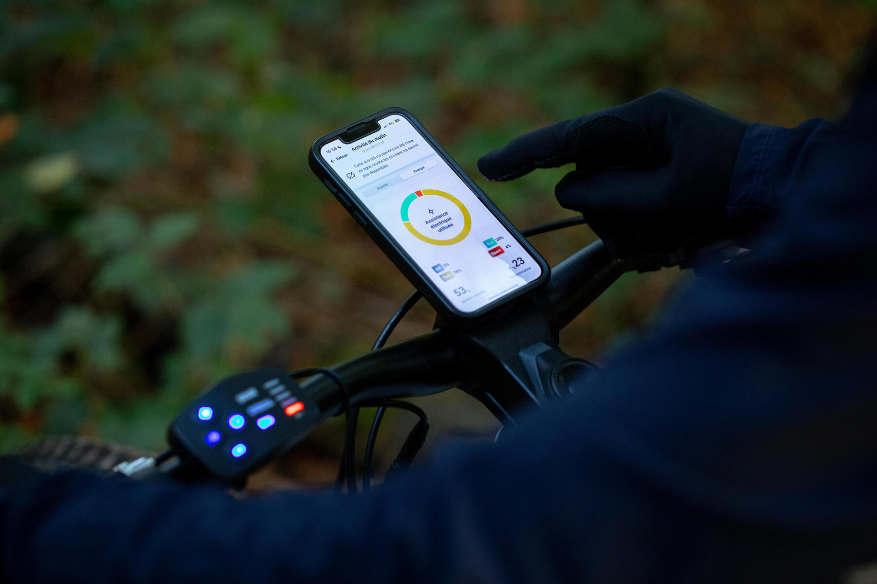 Osoba ustawiająca aplikację rowerową na telefonie umieszonym na kierwonicy rowerowej