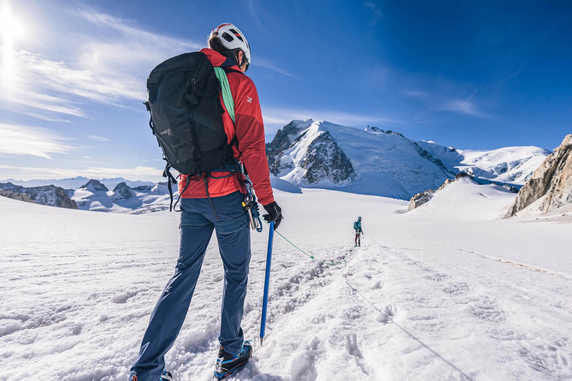 Alpinista idący po śniegu z czekanem