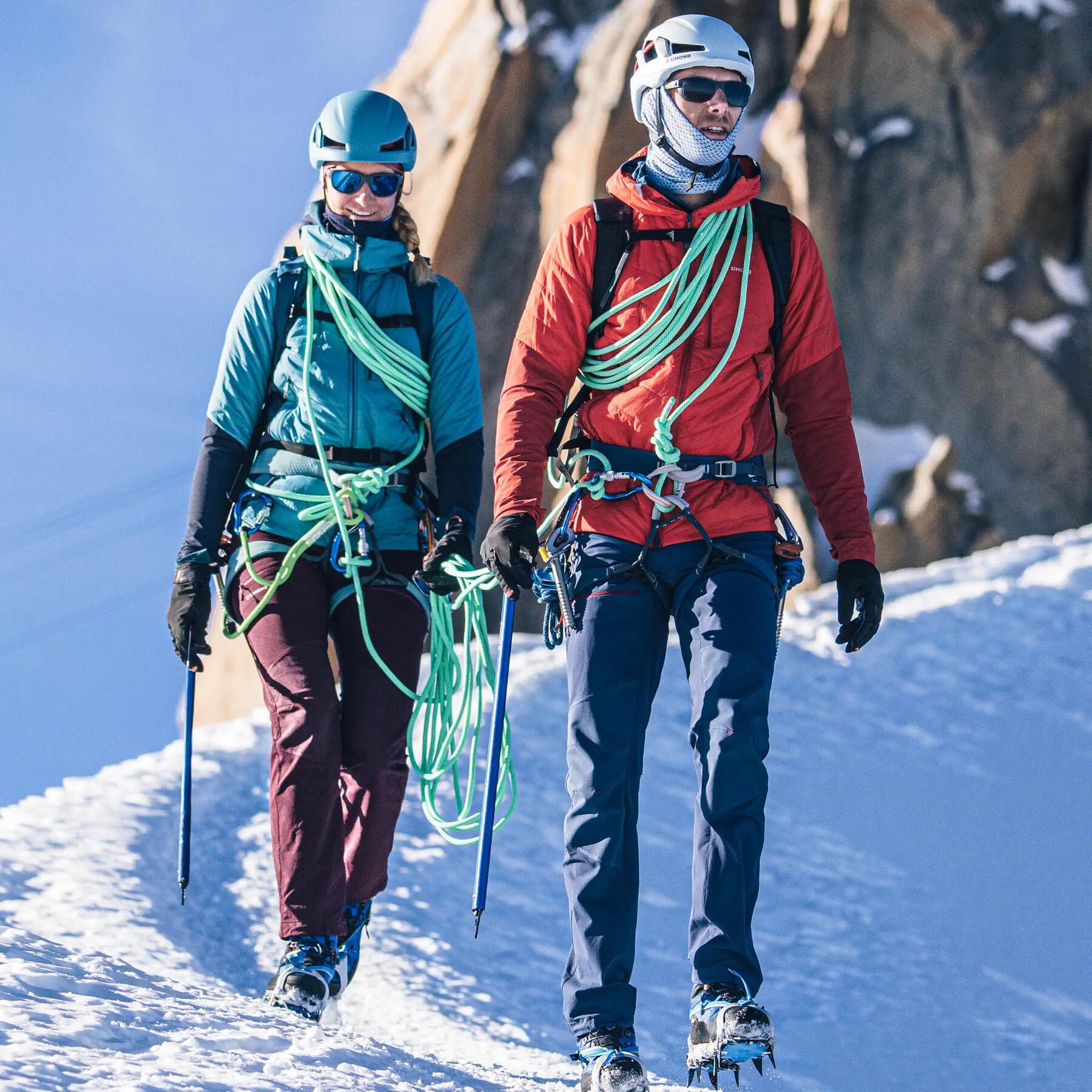 Mężczyzna i kobieta  wędrujący zimą w rakach po górach z czekanami i linami wspinaczkowymi