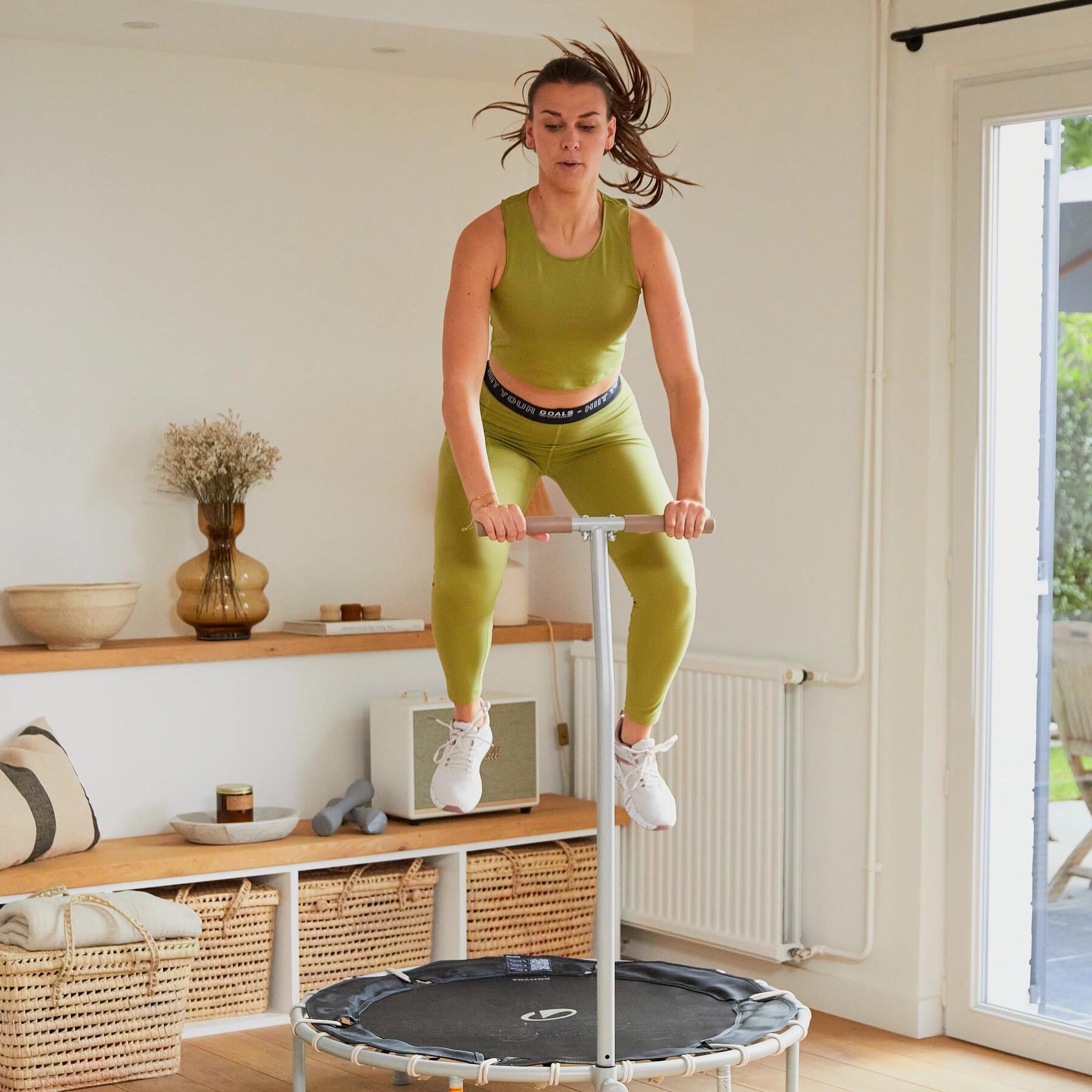 Eine Frau springt im Wohnzimmer auf einem Trampolin
