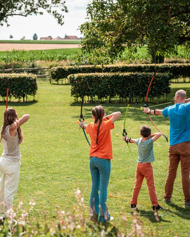 Familie im Garten ziehlt mit Bogenset auf Scheibe