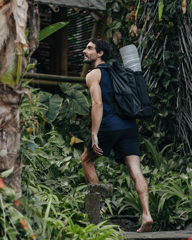 Ein Mann trägt eine Yogatasche im Wald.