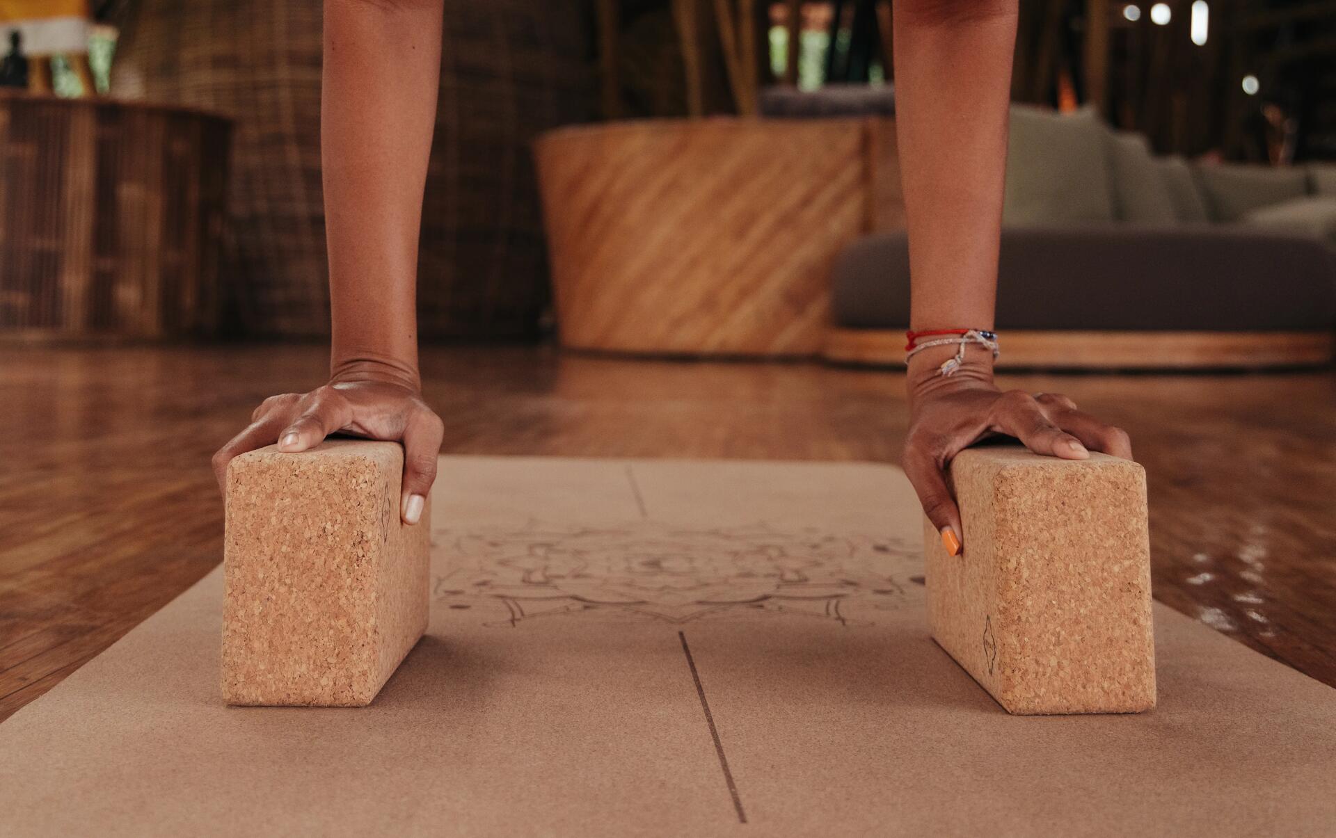 Homme s'appuyant sur un bloc de liège pour maintenir une pose de yoga