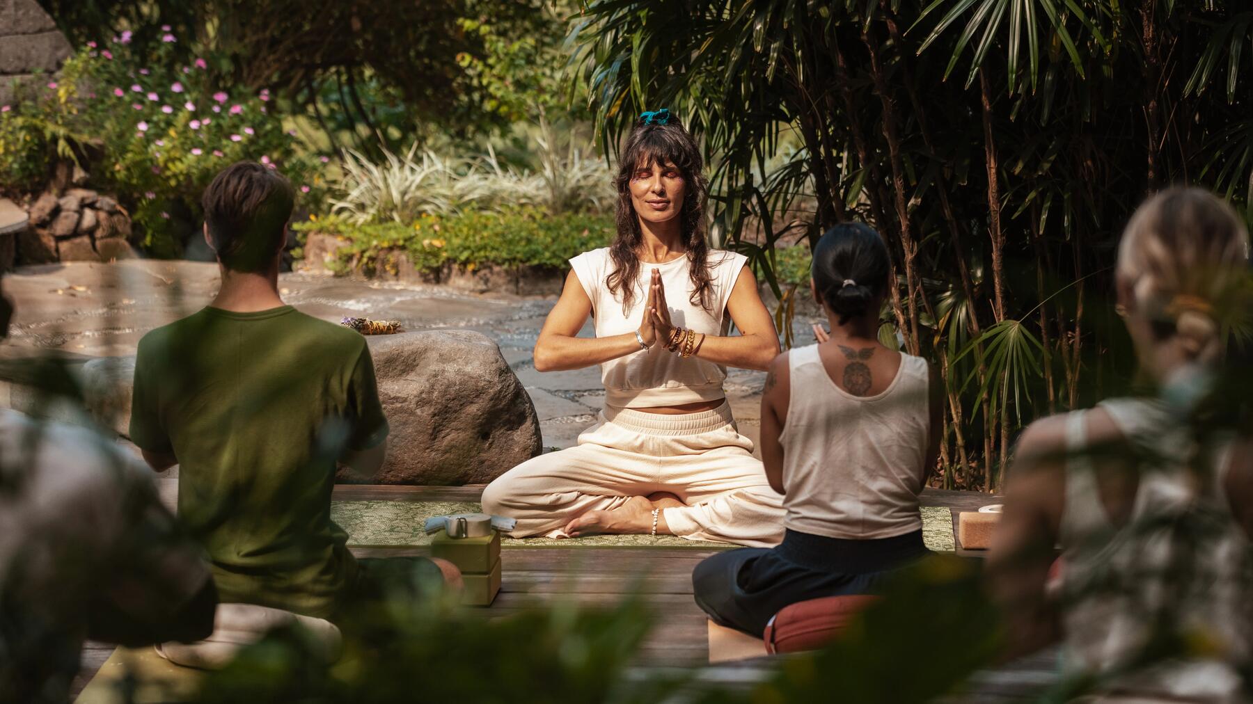 Gruppe macht Kundalini-Übungen auf Matten in der Natur