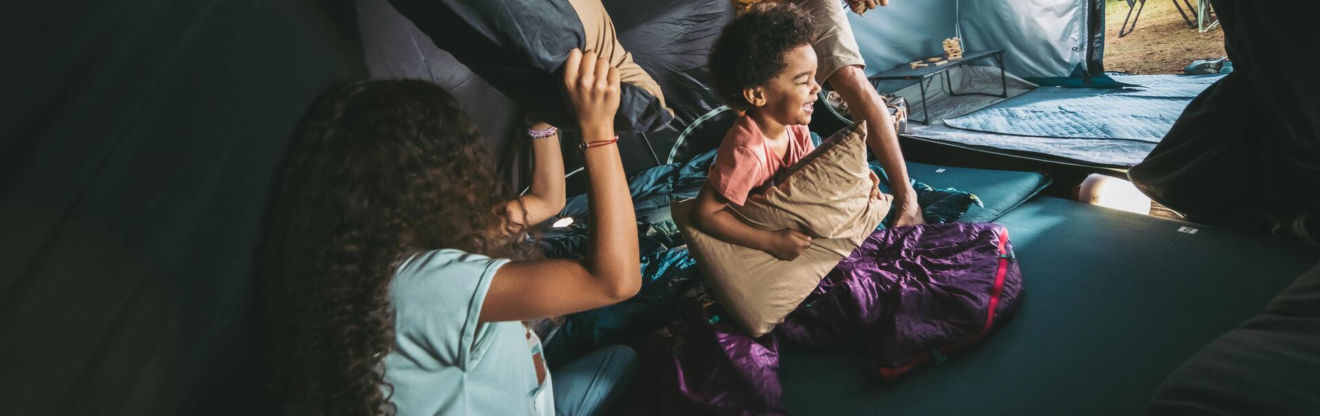 A family pillow fighting in a tent