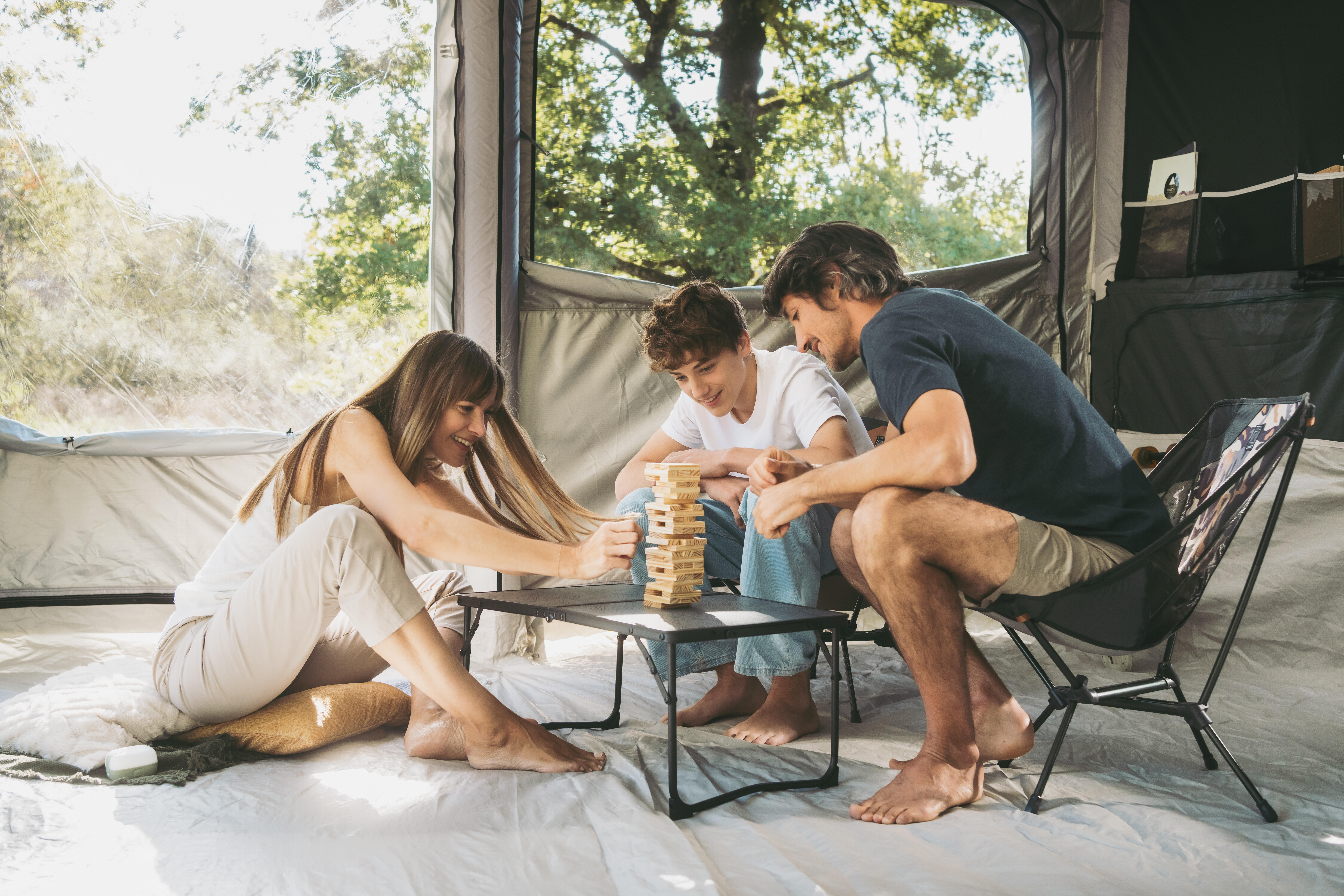 Family playing a stacking game around a kids picnic table inside a camping tent