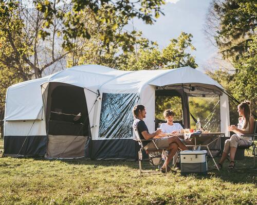 Ludzie siedzący przed namiotem i jedzący wspólnie posiłek