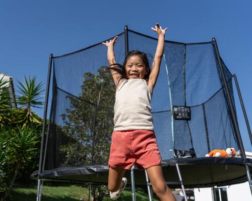 dziewczynka skacząca przed trampoliną ogrodową