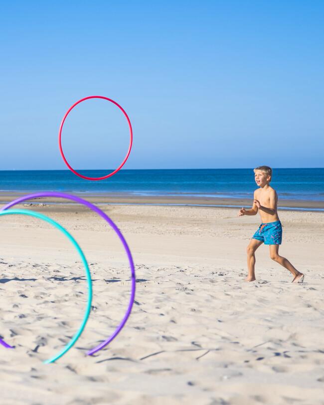 Ein Junge spielt am Strand mit Gymnastikreifen.