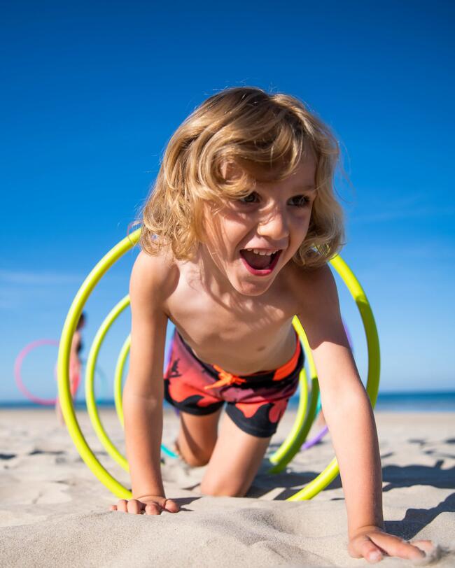 Ein Junge spielt am Strand mit Gymnastikreifen.
