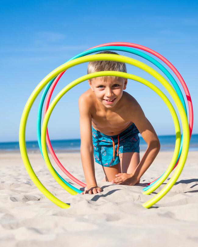 Ein Junge spielt am Strand mit Gymnasrikreifen.