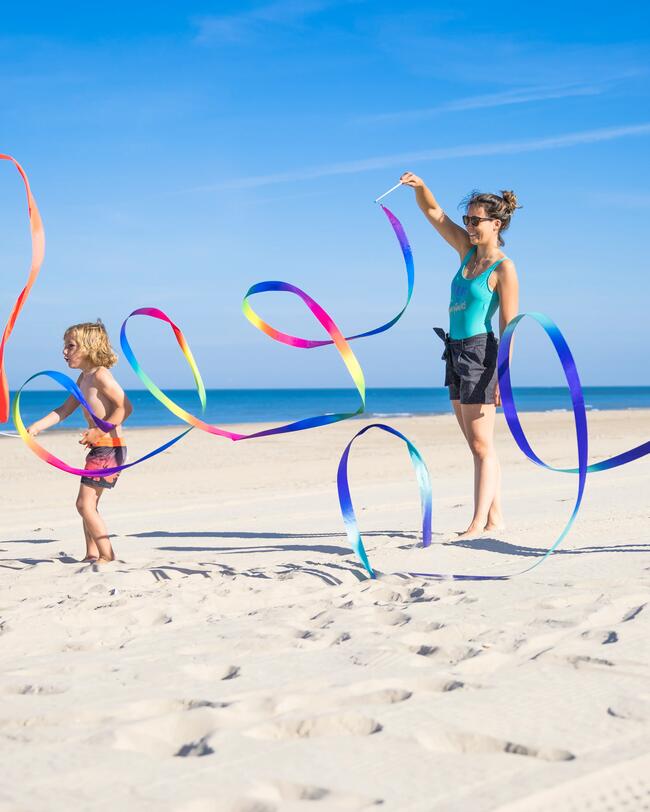 Eine Familie spielt am Strand mit Gymnastikbändern.
