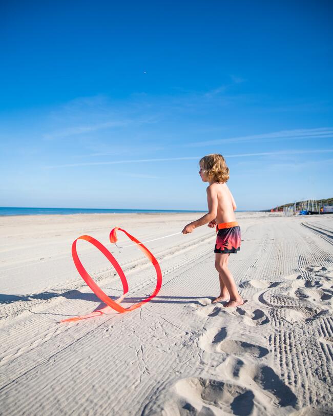 Ein Junge spielt am Strand mit einem Gymnastikband.