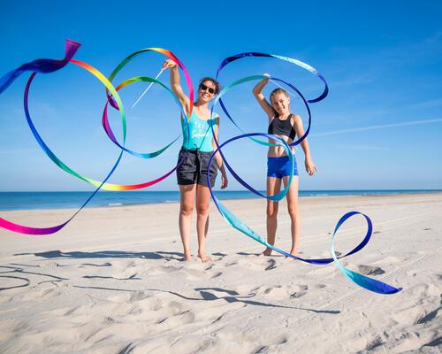 Kobiety w strojach sportowych na plaży uprawiające gimnastykę