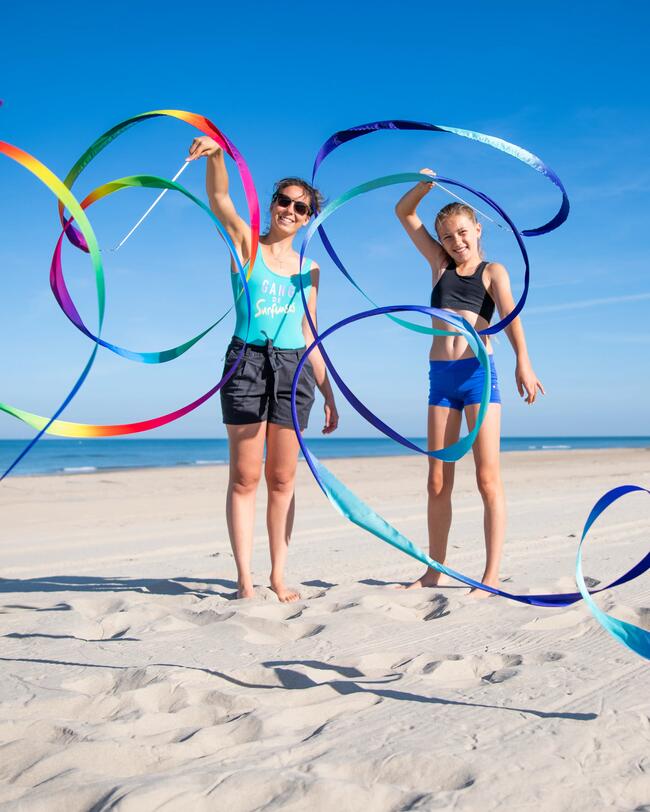 Zwei Personen stehen am Strand mit Gymnastikbändern.