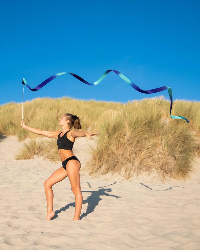 Ein Mädchen steht in Sportbekleidung am Strand.