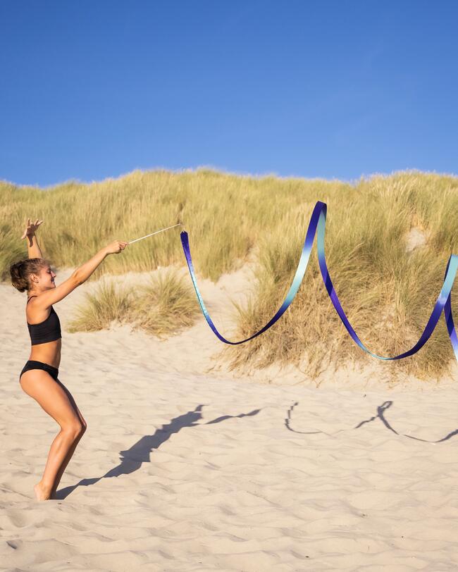 Ein Mädchen steht in Sportbekleidung am Strand.