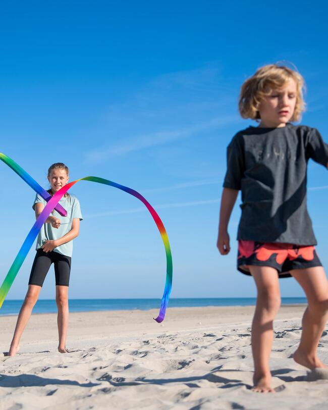 Zwei Kinder am Strand spielen mit Gymnastikbändern.