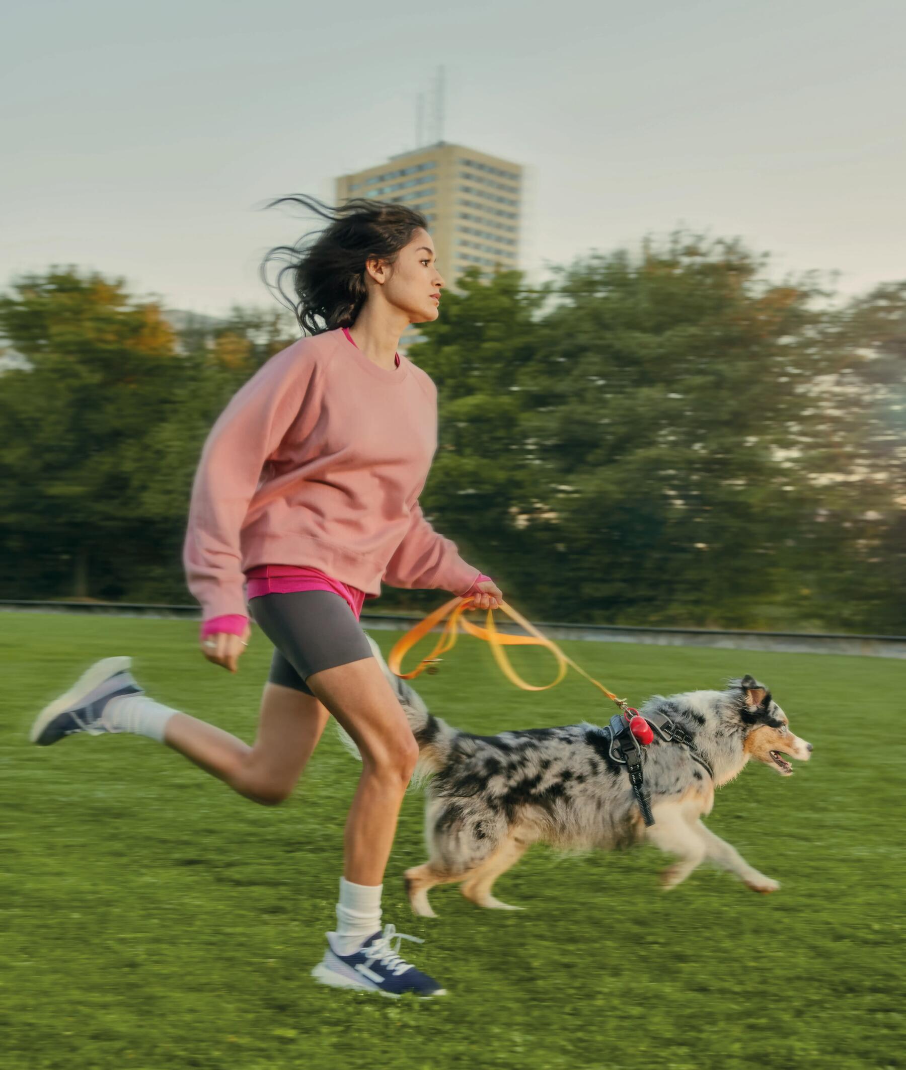 Dziewczyna w stroju sportowym biegająca po parku z psem