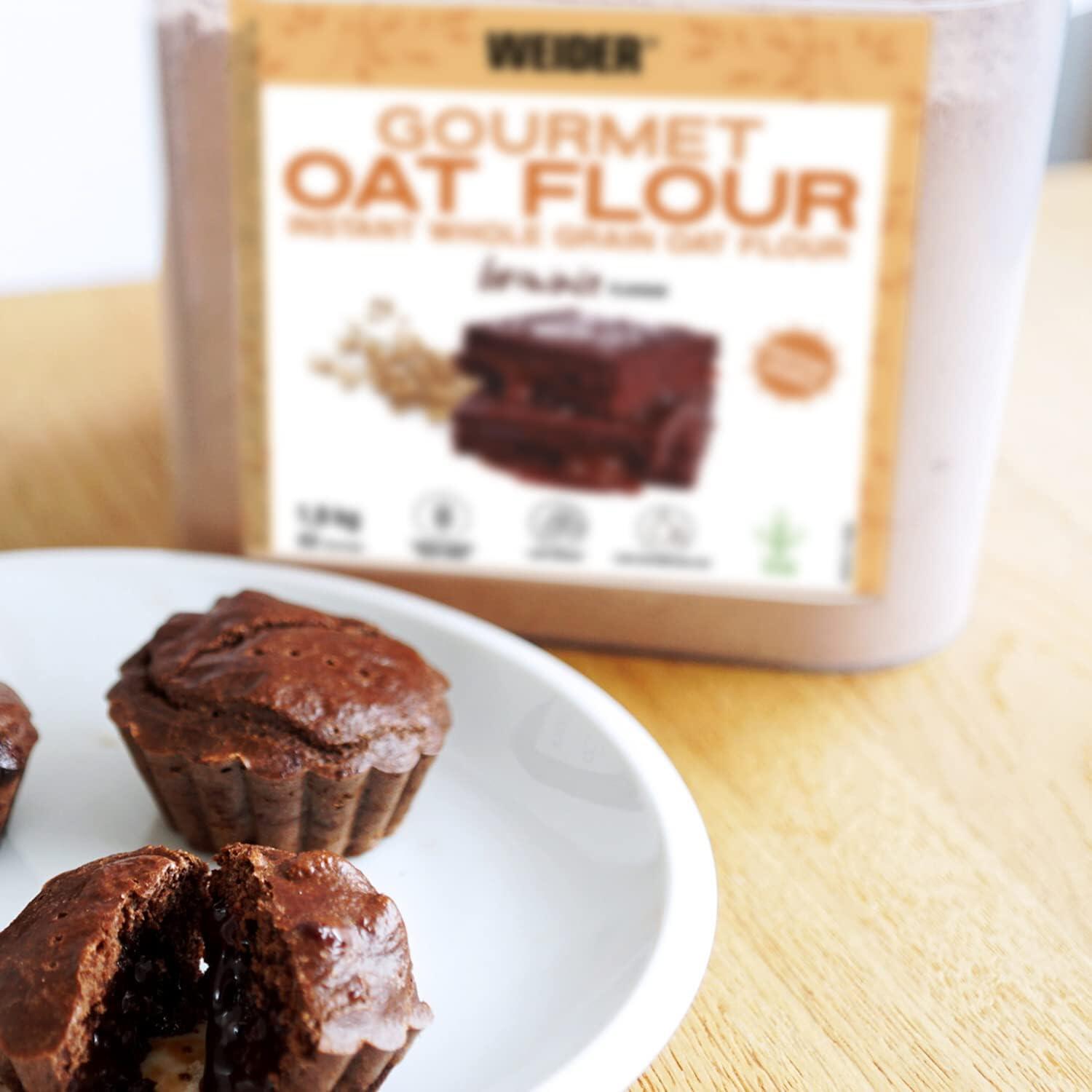 Schoko Protein Muffins auf weißem Teller auf braunem Holztisch, im Hintergrund Proteinpulver zu sehen.