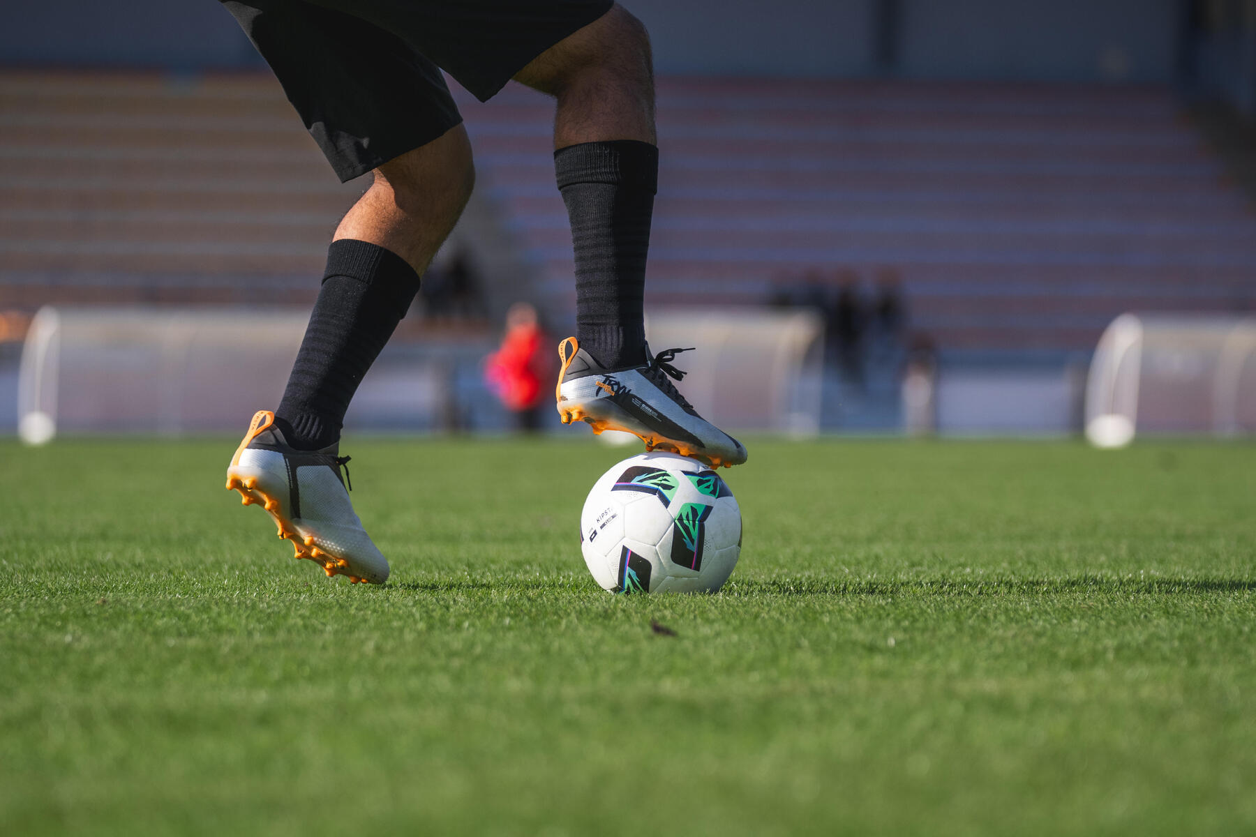 Piłkarz w odzieży i butach piłkarskich zatrzymujący nogą piłkę do piłki nożnej podczas treningu na jednym z największych stadionionów piłkarskich w Polsce
