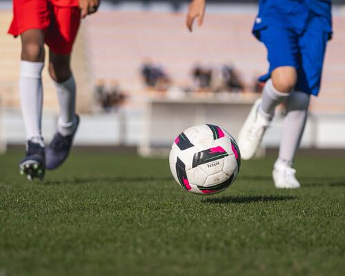 bola de futebol com duas pessoas a correr