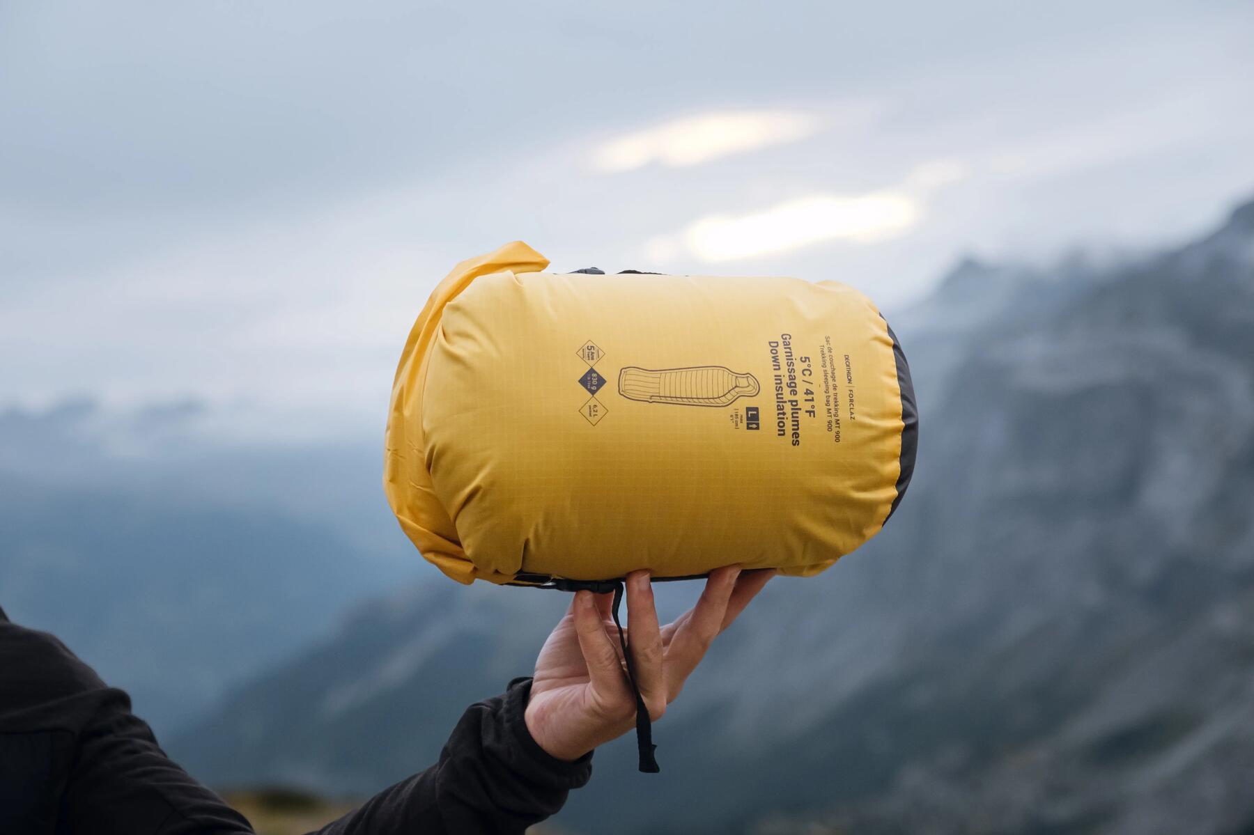 Eine Person hält einen zusammengerollten Schlafsack