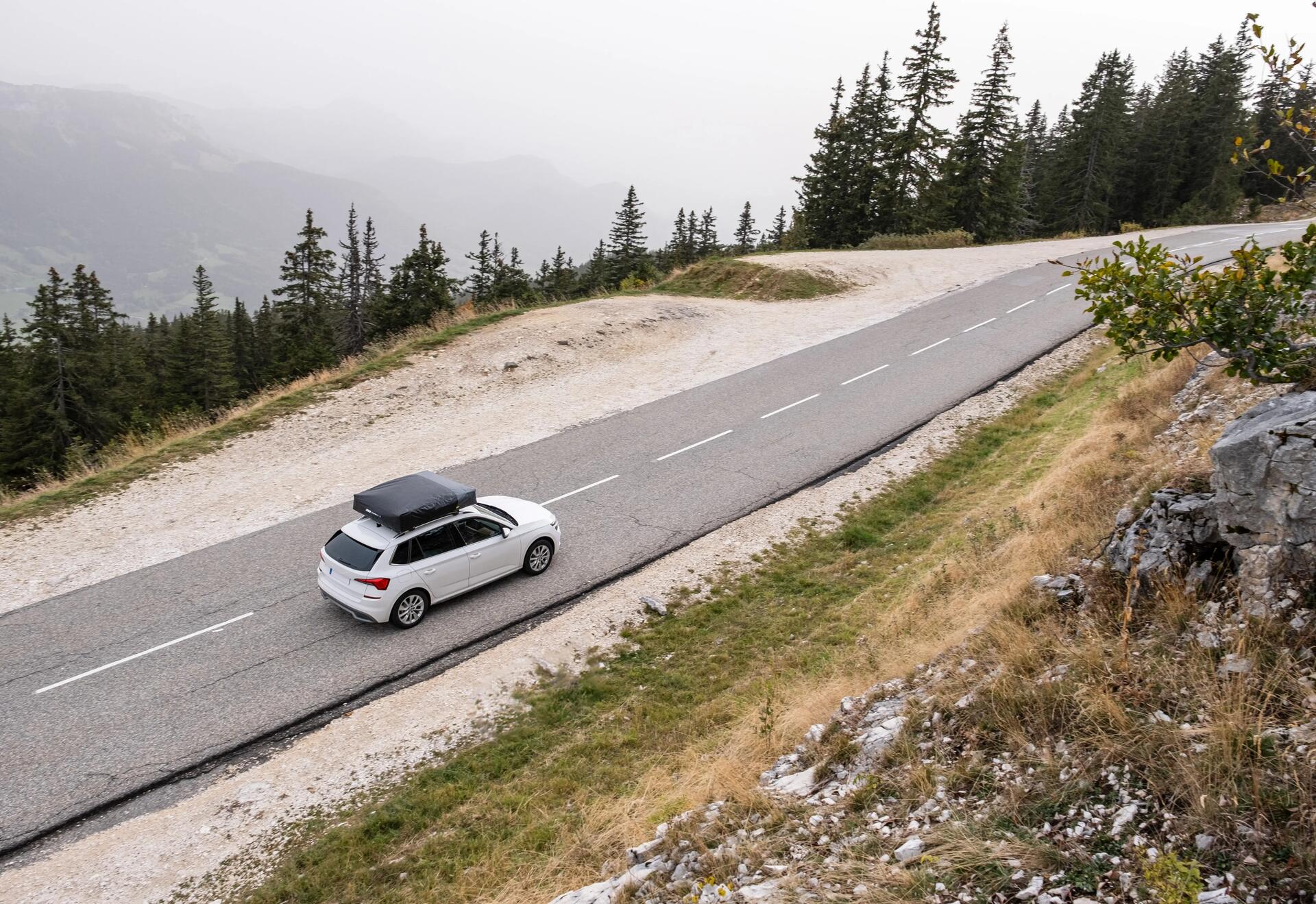 Auto z bagażem na dachu jadące w góry trasą asfaltową