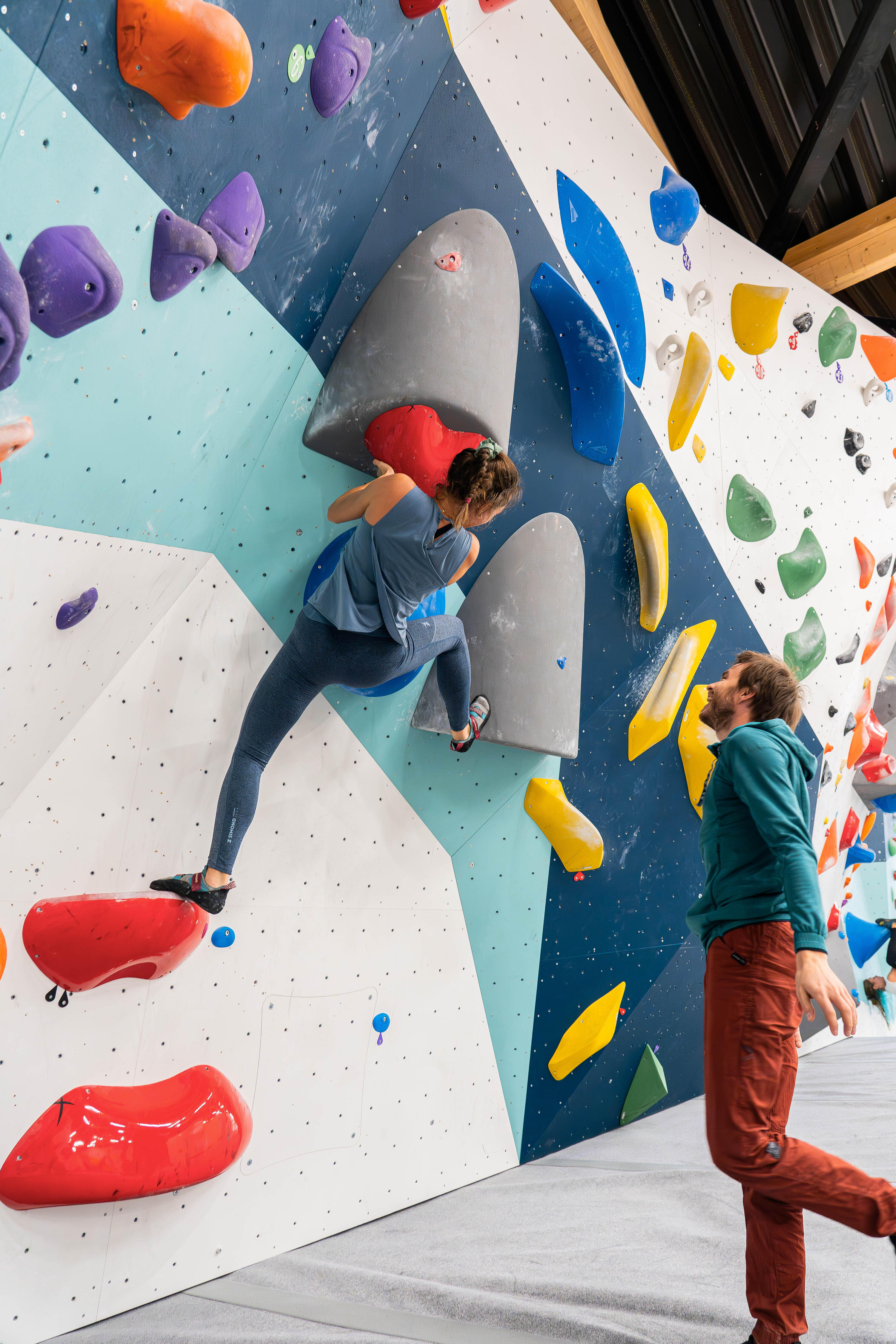 Ein Mädchen klettert in einer Boulderhalle und schaut sich nach dem nächsten Schritt für ihre Kletterroute um.