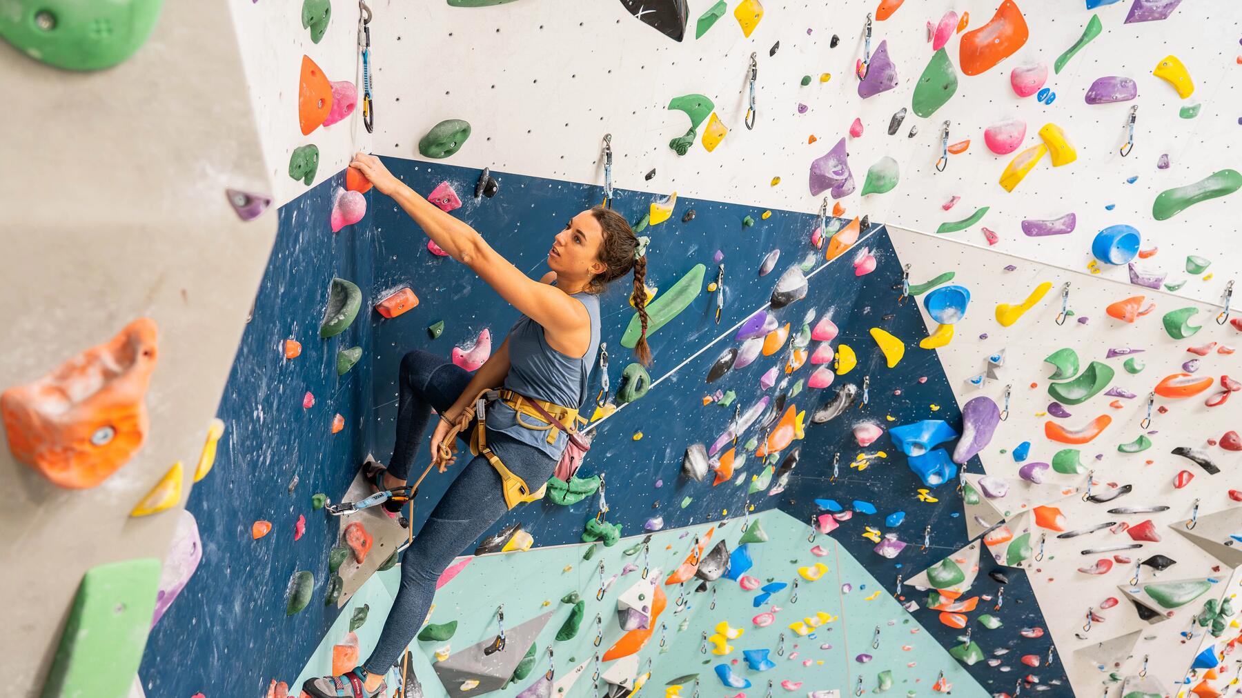grimpeuse monte sur un mur d'escalade intérieur à toute vitesse