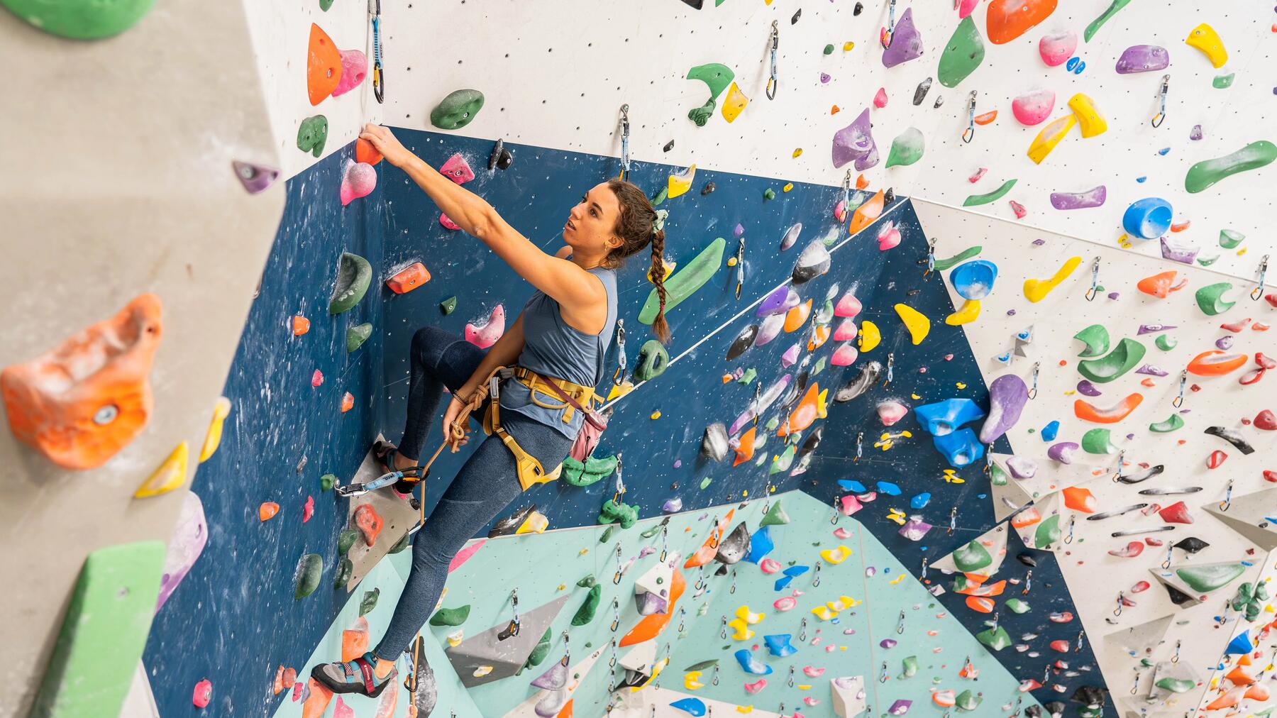 grimpeuse monte sur un mur d'escalade intérieur à toute vitesse