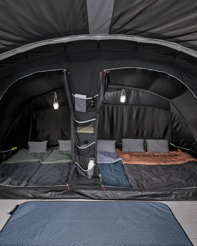 Zelt aufgebaut mit zwei Kammern, in welchen Schlafsäcke und Kissen liegen, mit Campinglampe darüber