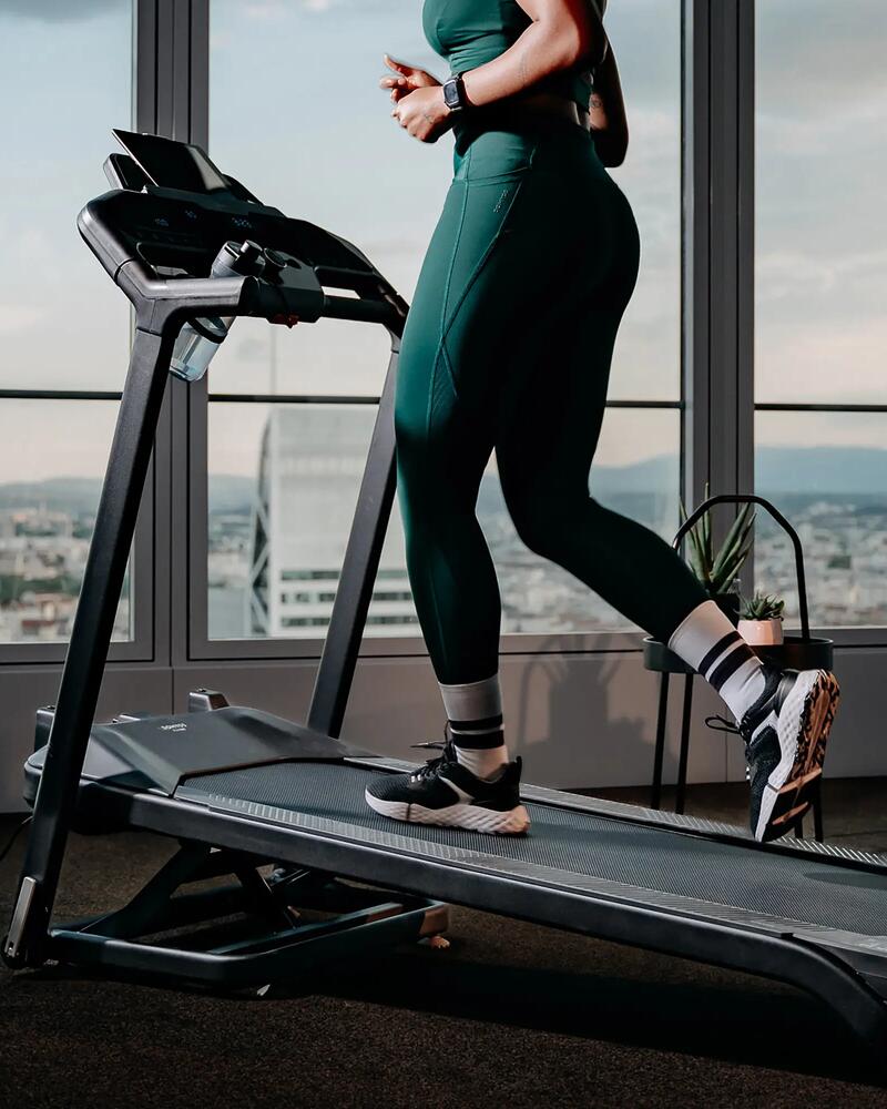 Eine Person nutzt ein Laufband mit Ausblick von einem Hochhaus-Fenster