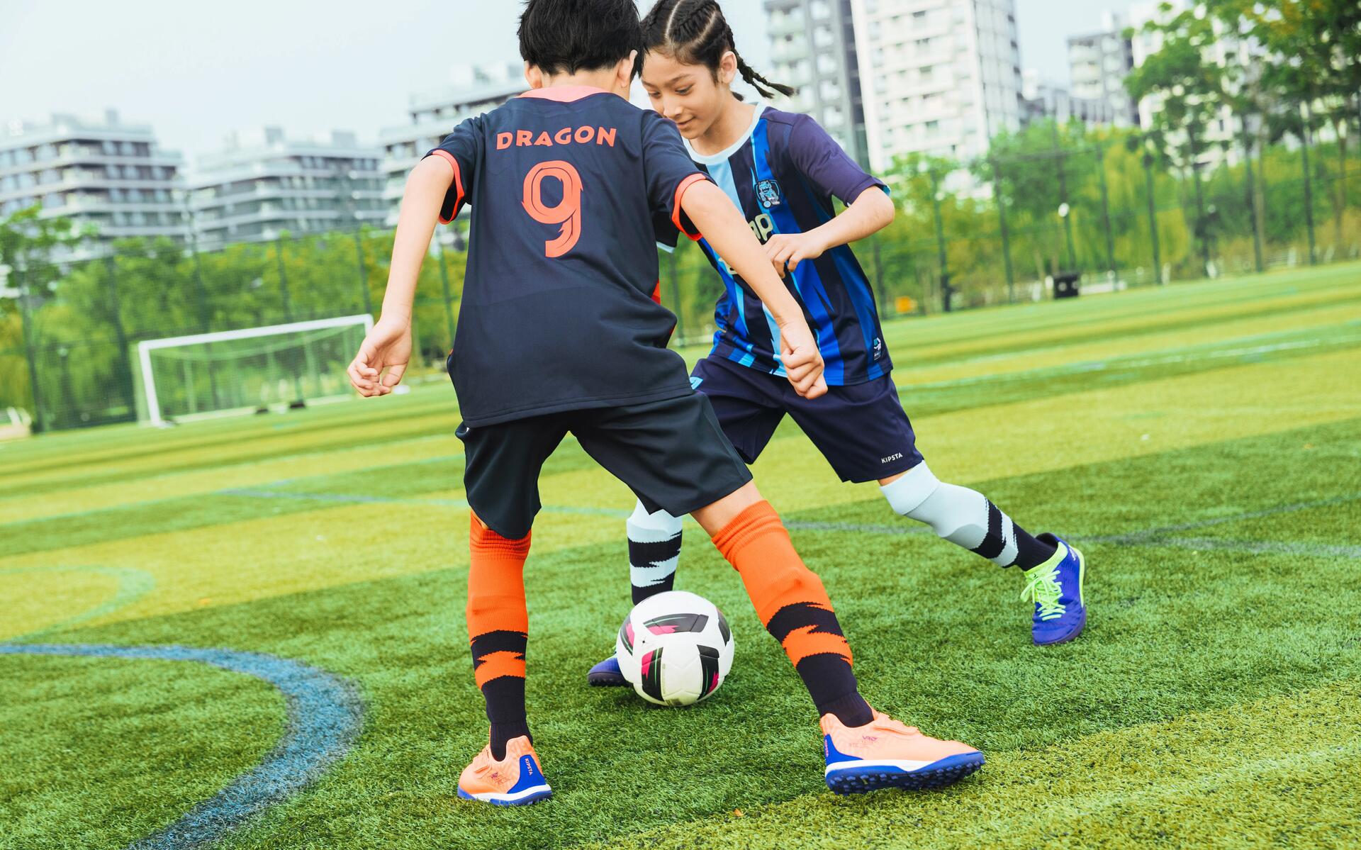 chłopcy w odzieży piłkarskiej walczący o piłkę podczas treningu piłkarskiego na boisku