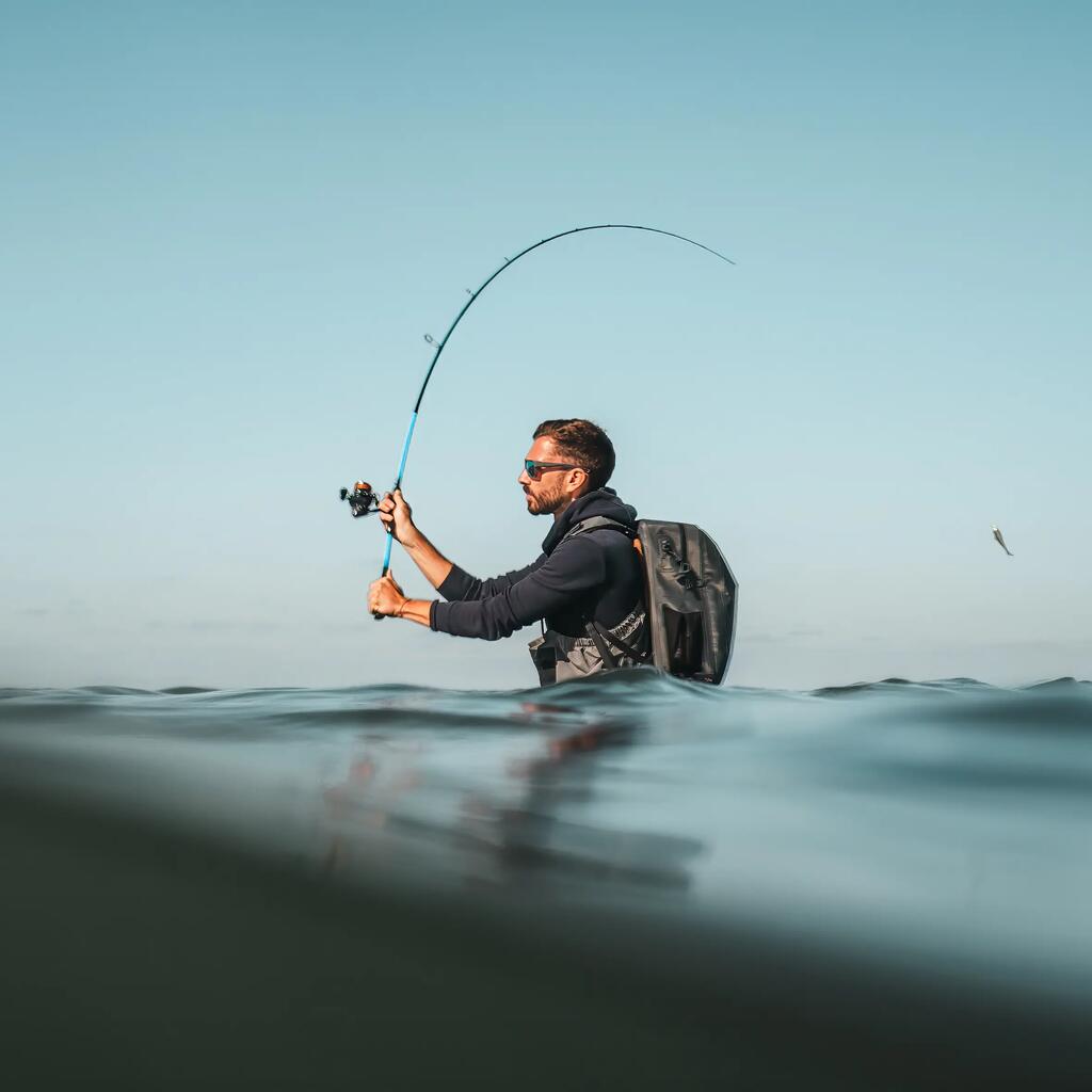 Ein Angler steht im Wasser und wirft gerade seine angelrute aus