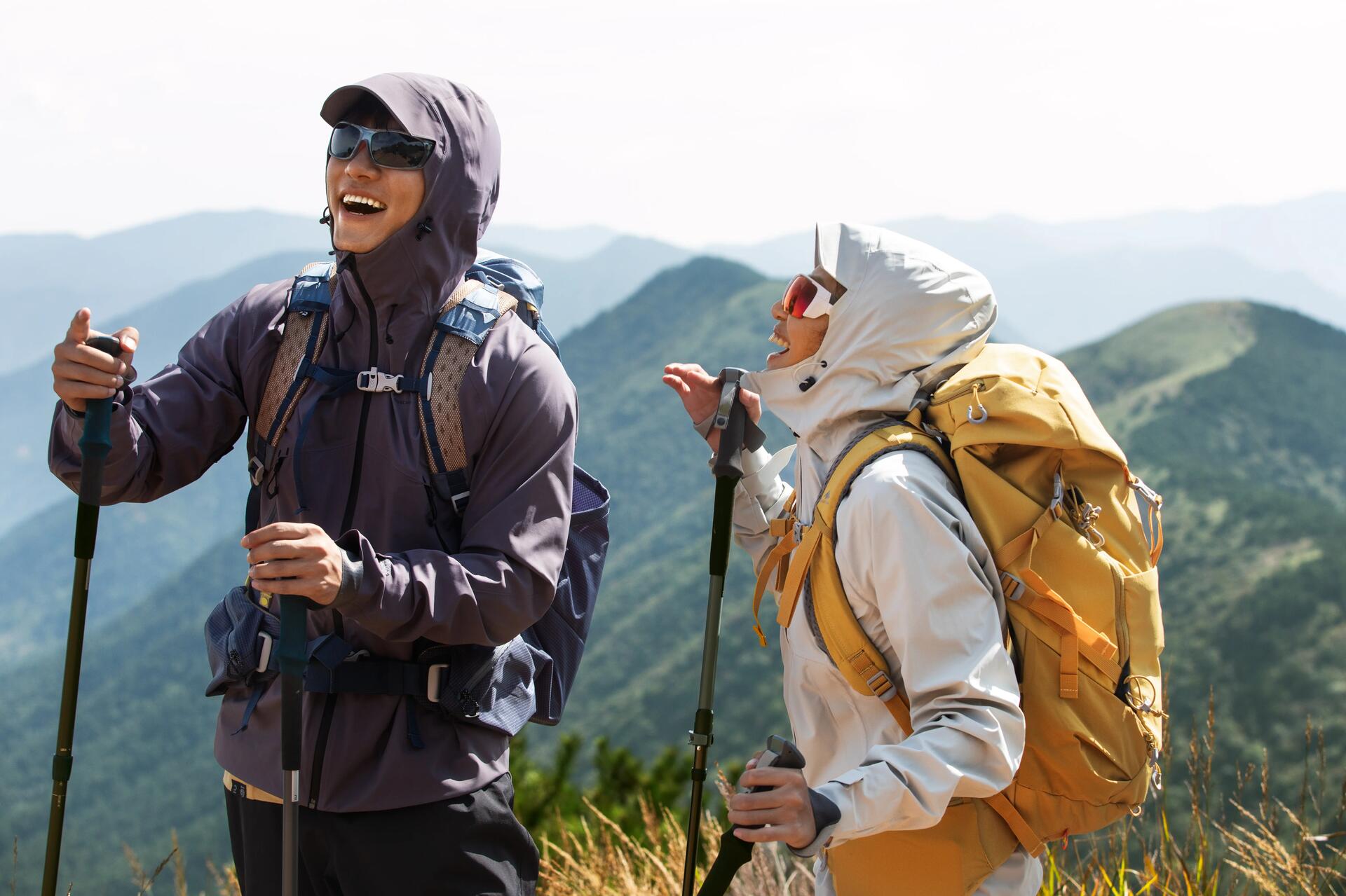 Kobieta i mężczyzna z założonymi okularami w góry stojący na szlaku trzymając kije trekkingowe w rękach