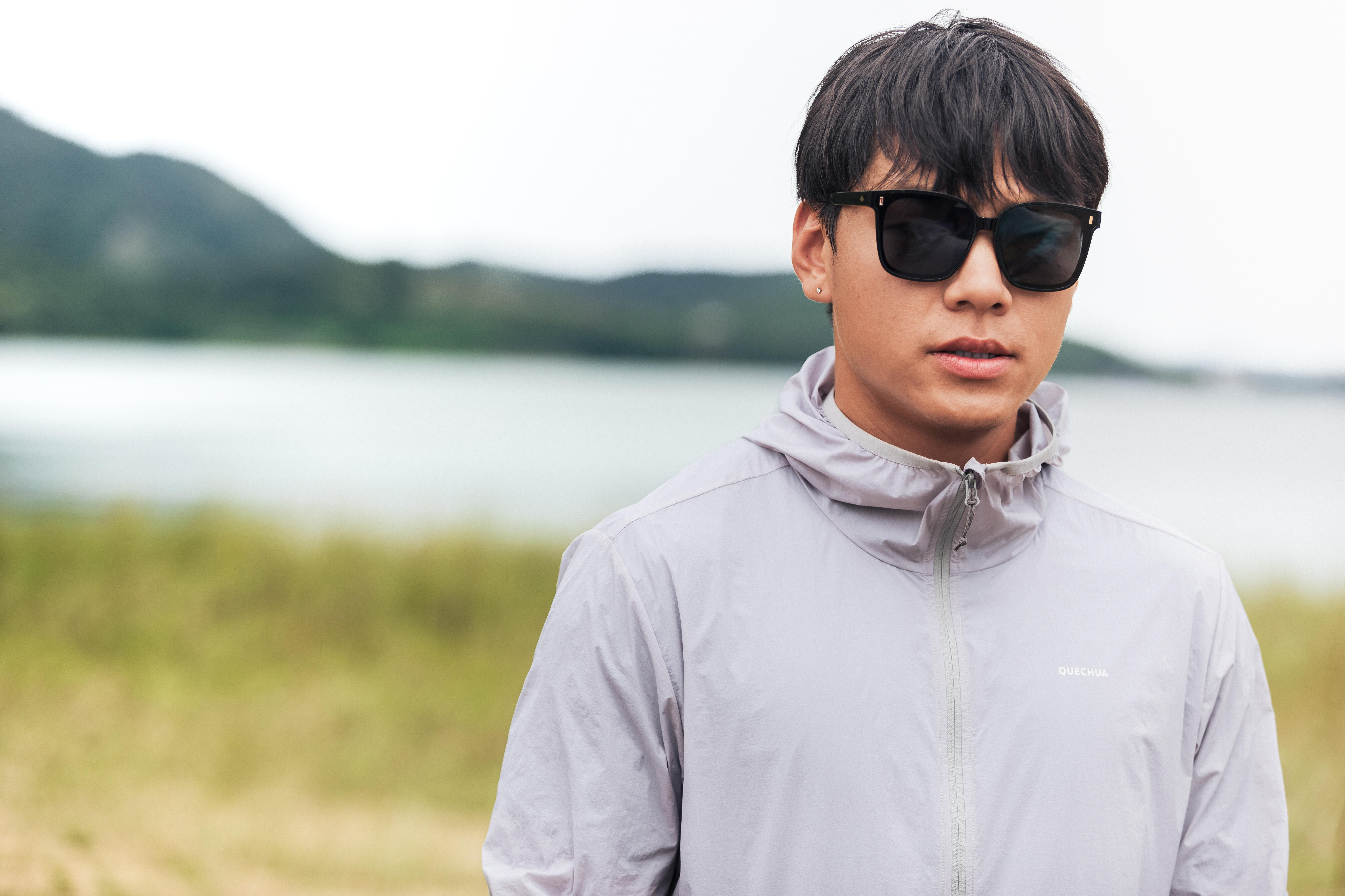 Man wearing black UV protection sunglasses outdoors beside a lake