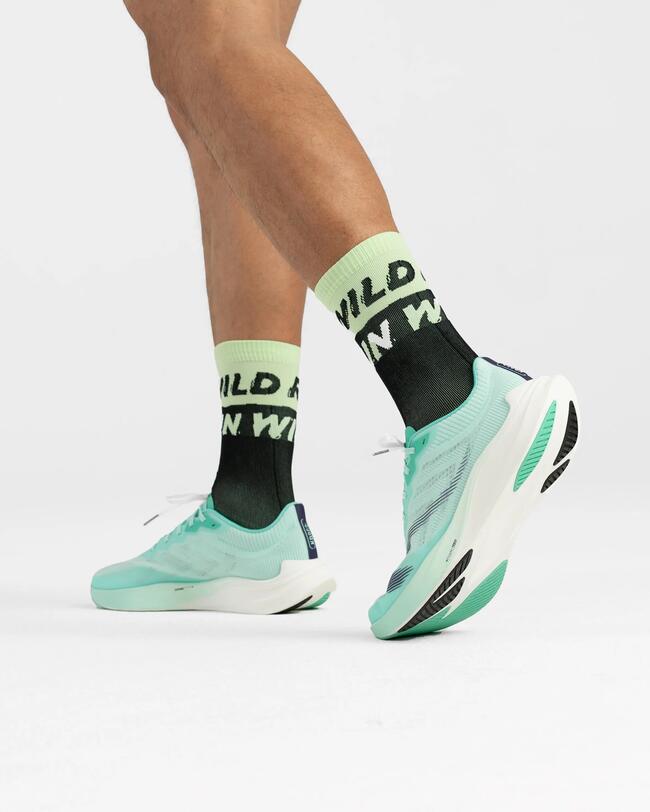 Türkise Laufschuhe und schwarze Socken auf weißem Hintergrund, grüner Schriftzug auf den Socken.