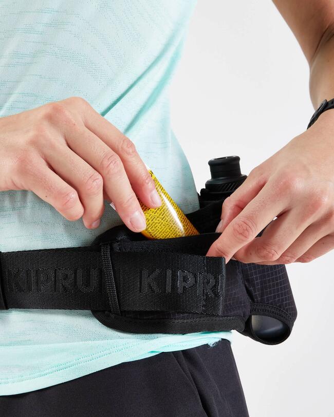 Nahaufnahme einer Person, die ein Gel-Päckchen aus der Tasche eines schwarzen Laufgürtels zieht.