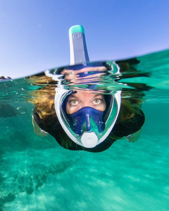 Woman snorkeling, front view, wearing Easybreath snorkel mask (women's/men's) with acoustic valve, 540 FT blue, and neoprene shorty wetsuit.