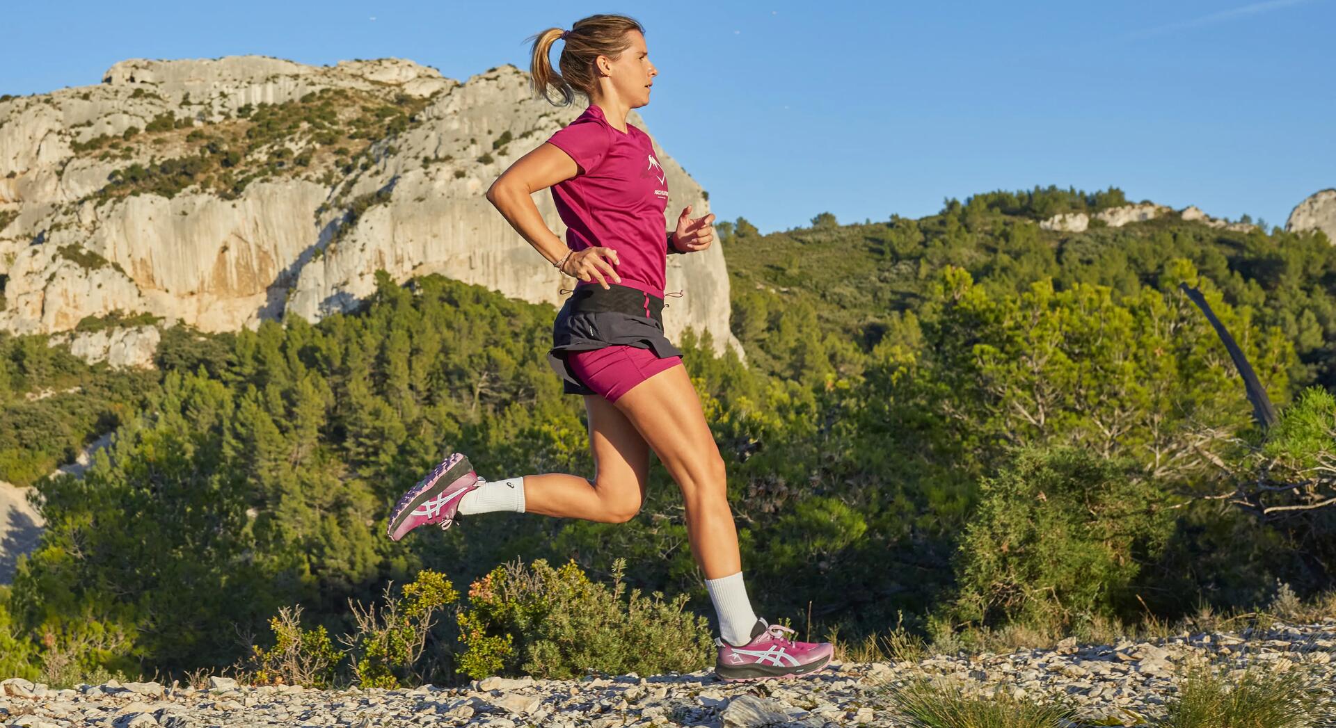 kobieta w butach i odzieży sportowej biegnąca  w terenie